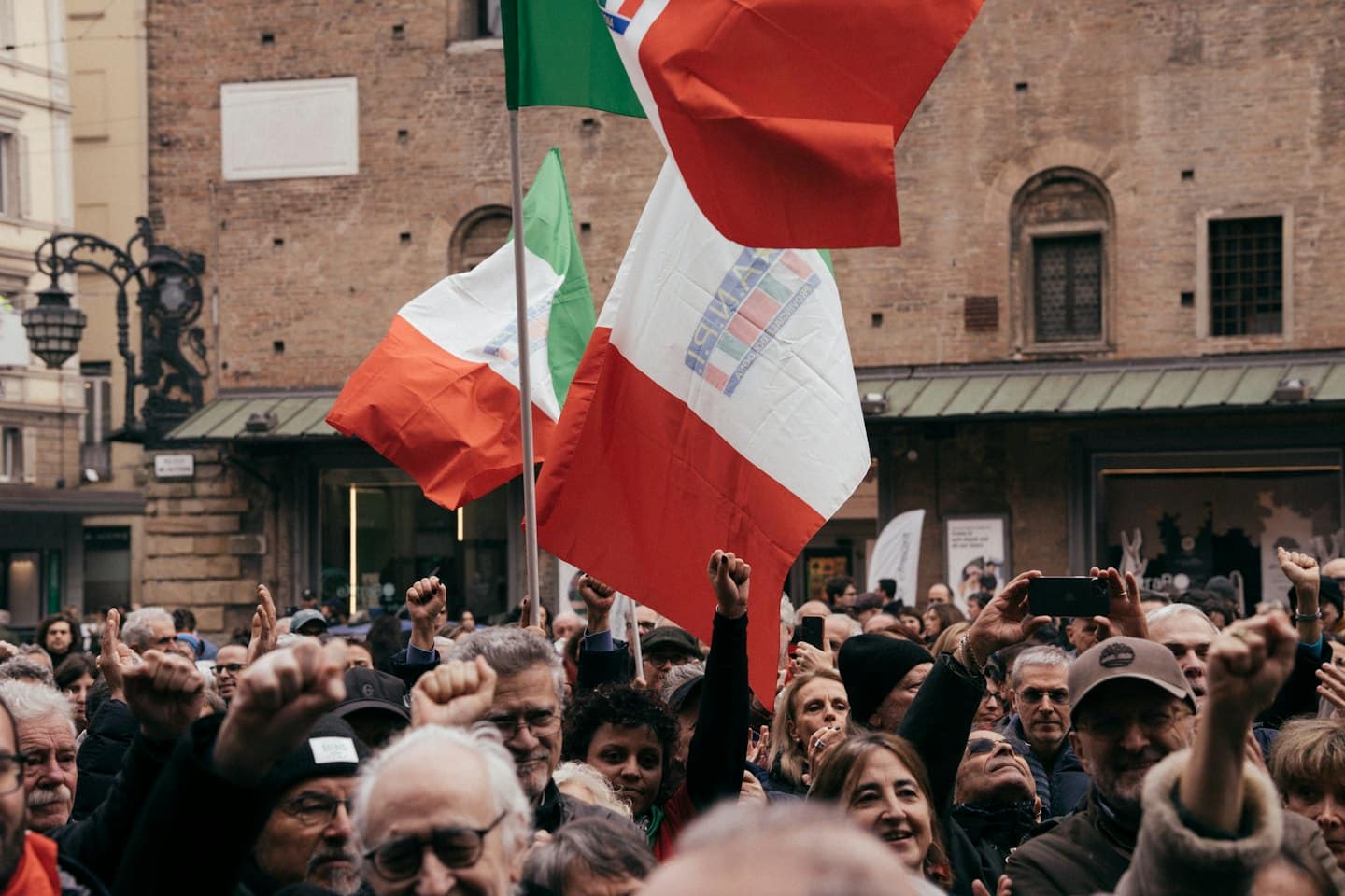 Folla di manifestanti con bandiere italiane durante una manifestazione.