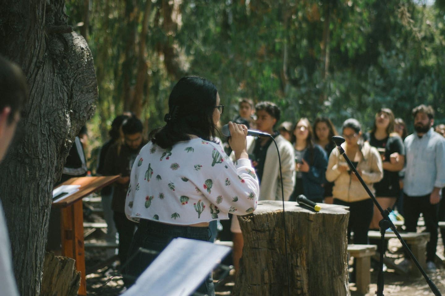 Donna parla al microfono su un leggio di legno all'aperto.